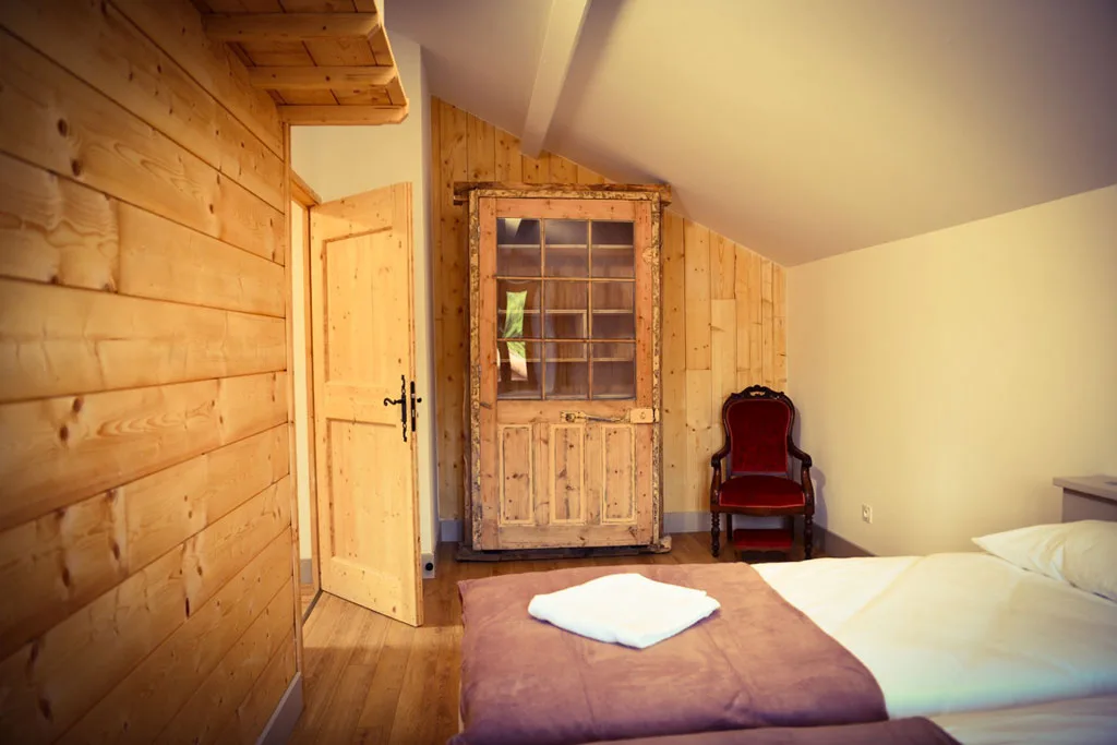 Chambre mansardée aux murs et plafond habillés de bois clair