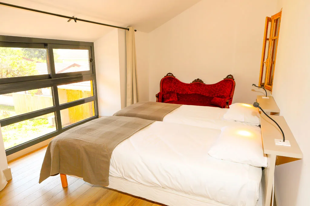 Chambre avec lit double, tête de lit capitonnée rouge et grande baie vitrée