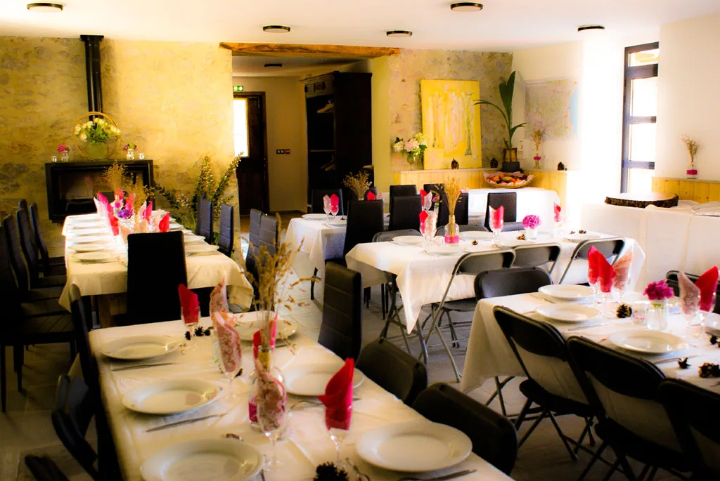 Grande salle de réception dressée pour un repas de groupe avec tables et chaises