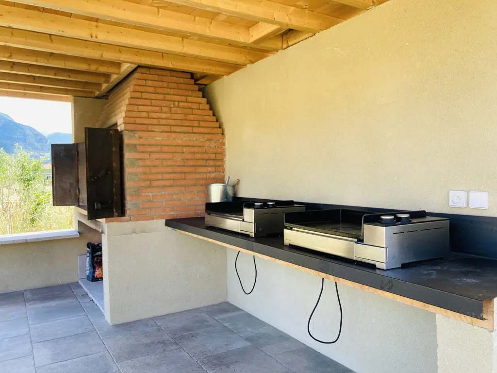 Coin barbecue et plancha extérieur couvert avec four à bois en briques