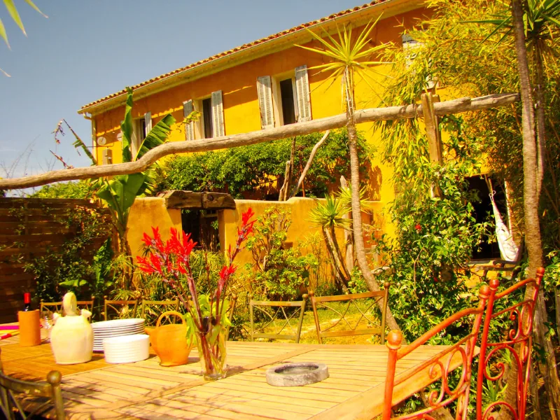 Façade ocre provençale du mas avec terrasse et boulodrome ombragé