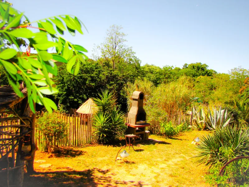 Jardin avec barbecue et coin repas extérieur entouré de verdure