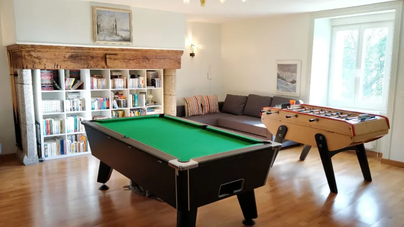Salle de jeux avec billard et baby-foot sous cheminée en pierre