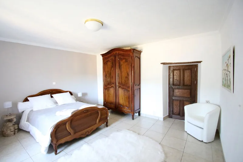 Chambre avec lit ancien en bois sculpté et armoire provençale