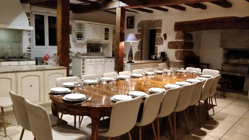 Grande salle à manger avec table dressée pour vingt convives et cheminée en pierre