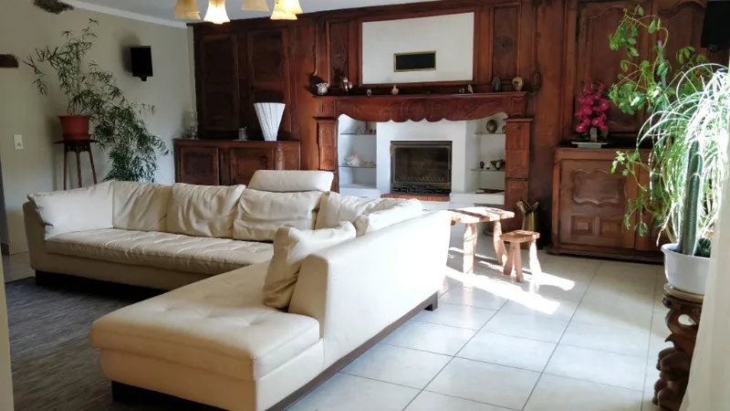Grand salon avec canapés en cuir blanc et cheminée en bois sculpté
