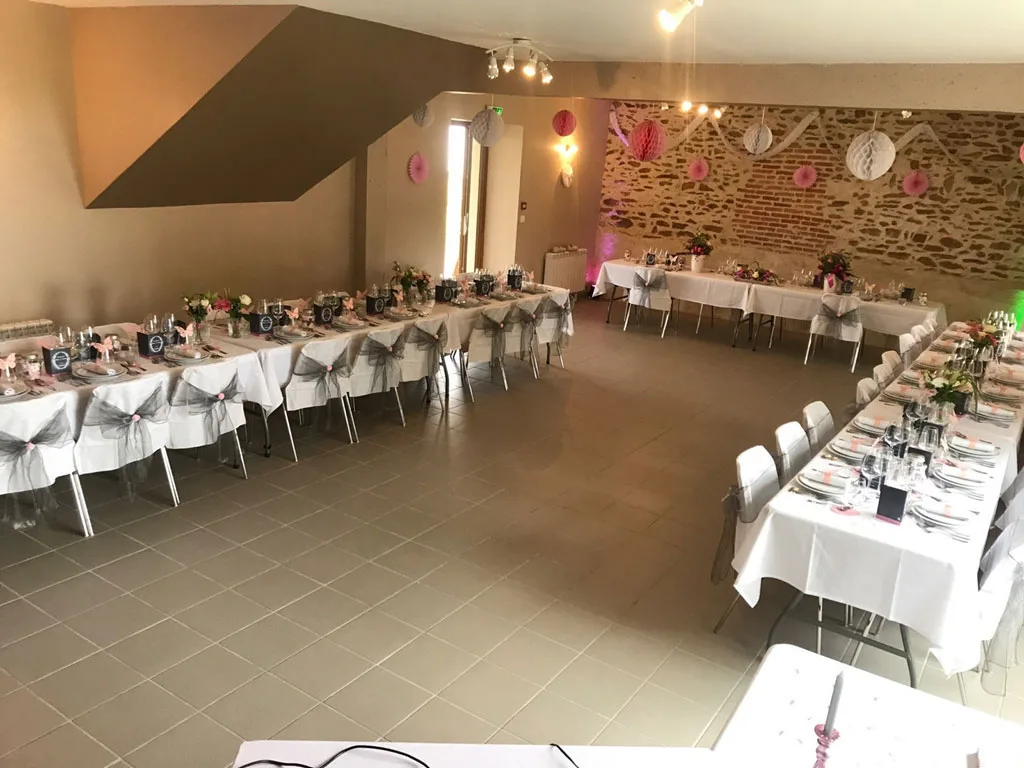 Salle de réception décorée pour un mariage avec tables dressées en rose et gris