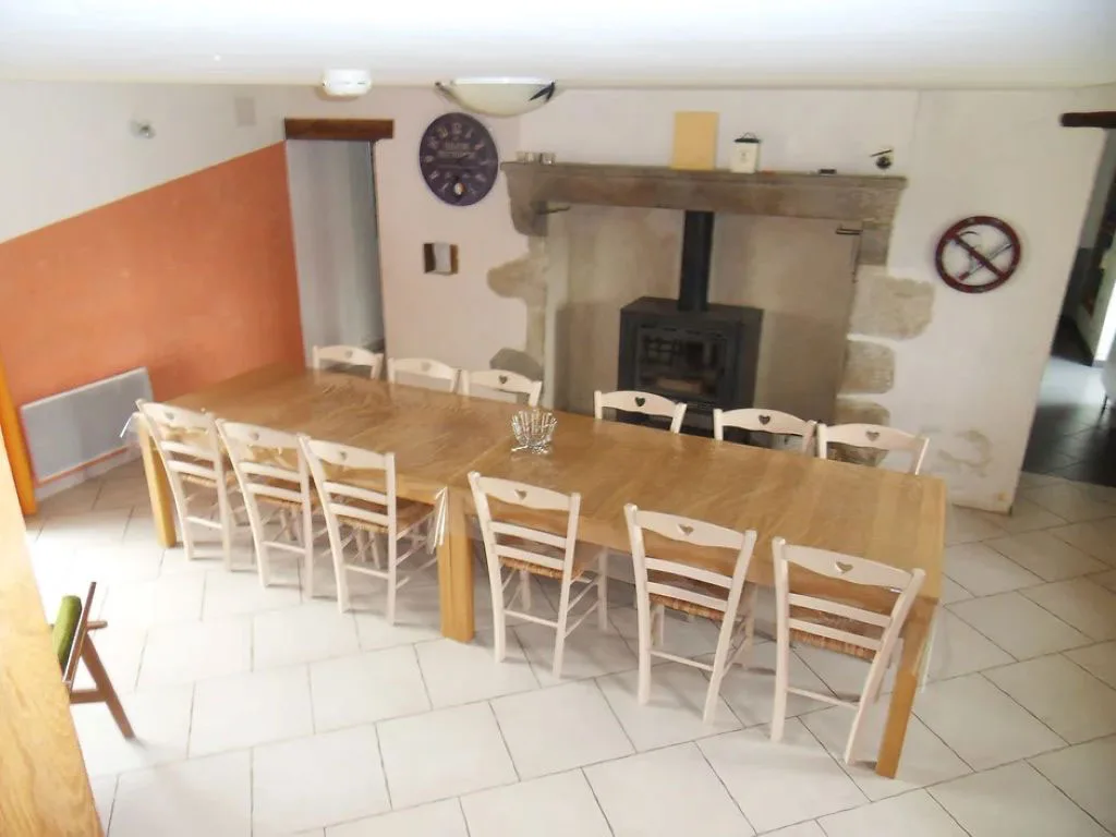 Grande salle à manger avec longue table en bois et poêle à bois traditionnel