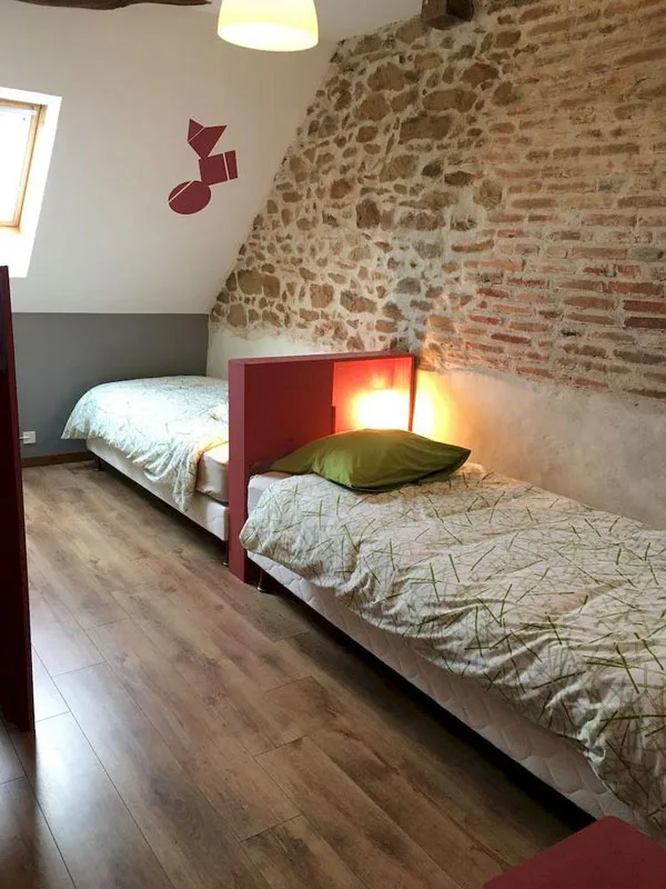 Chambre mansardée avec pierres apparentes et lits simples