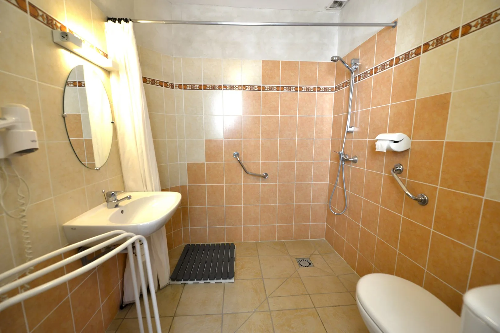 Salle de bain accessible PMR avec douche à l'italienne et barres d'appui