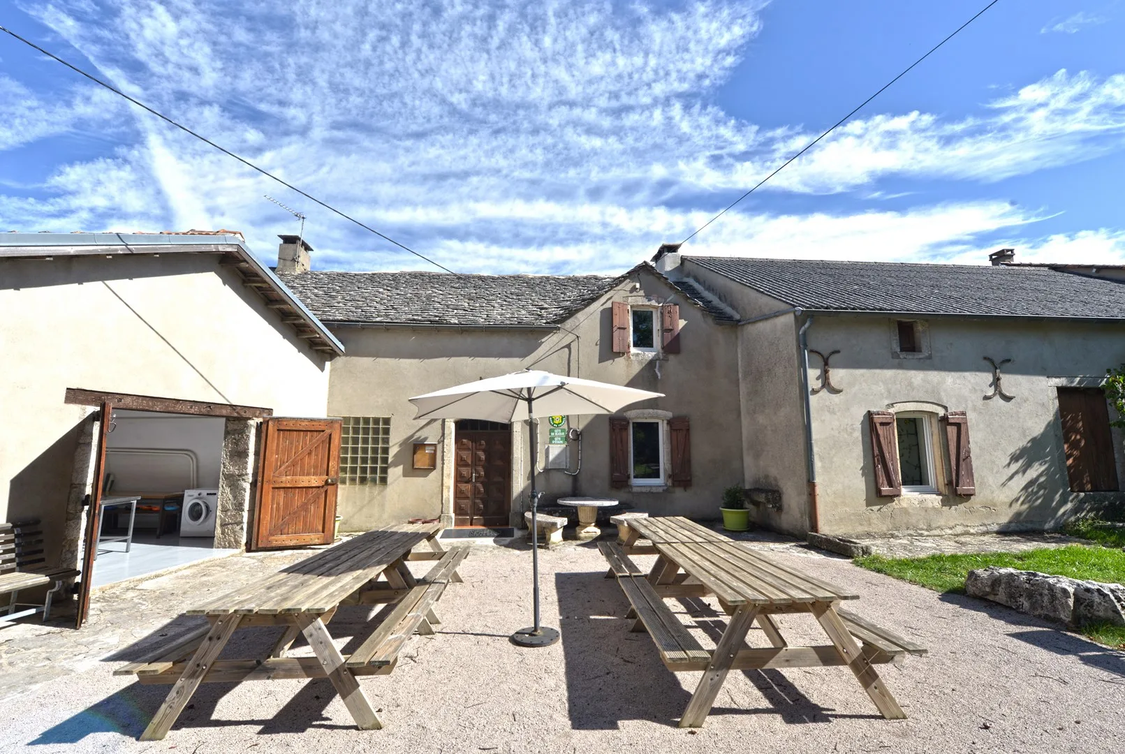 Vue extérieure de la façade en pierre avec terrasse et tables de pique-nique