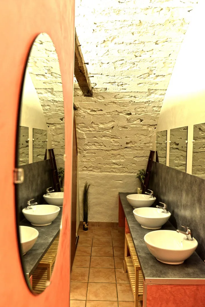 Salle d'eau collective avec trois vasques et miroirs pour les groupes