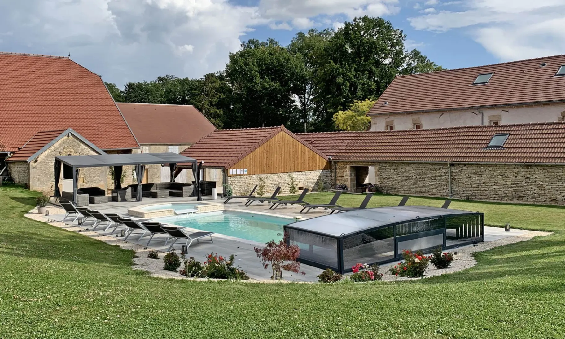 Vue d'ensemble de la piscine, du jacuzzi et des bâtiments en pierre