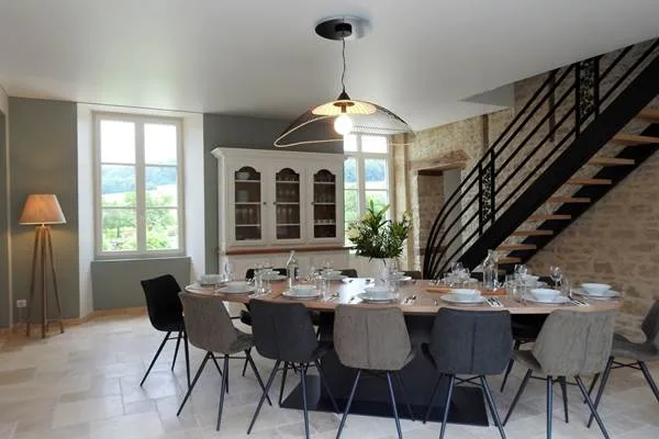 Grande salle à manger avec table dressée pour un groupe et vaisselier ancien