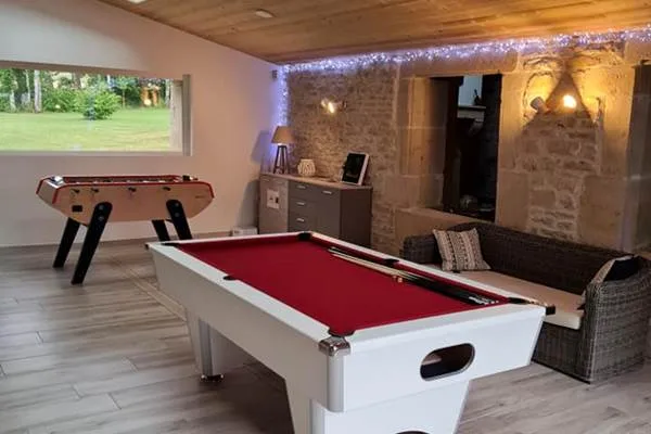 Salle de jeux avec billard, baby-foot et mur en pierres apparentes