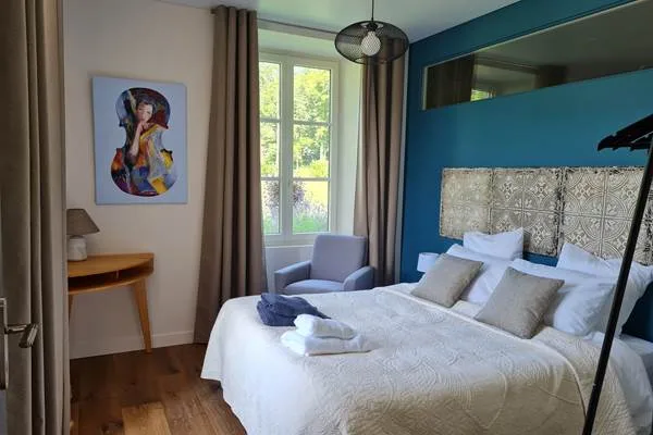 Chambre avec mur bleu paon, tête de lit capitonnée et coussins assortis
