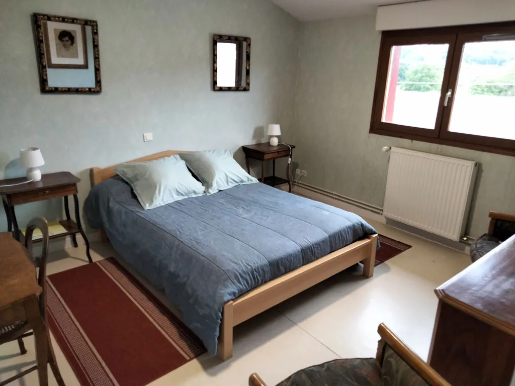 Chambre double avec couvre-lit bleu et vue sur la campagne