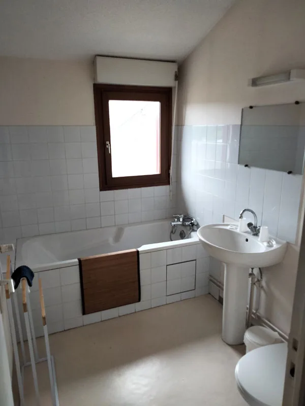 Salle de bain avec baignoire, lavabo et fenêtre en bois