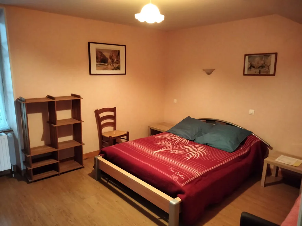 Chambre double avec couvre-lit bordeaux et mobilier en bois
