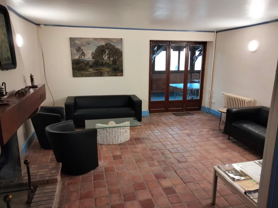 Salon avec canapés en cuir noir et cheminée en pierre