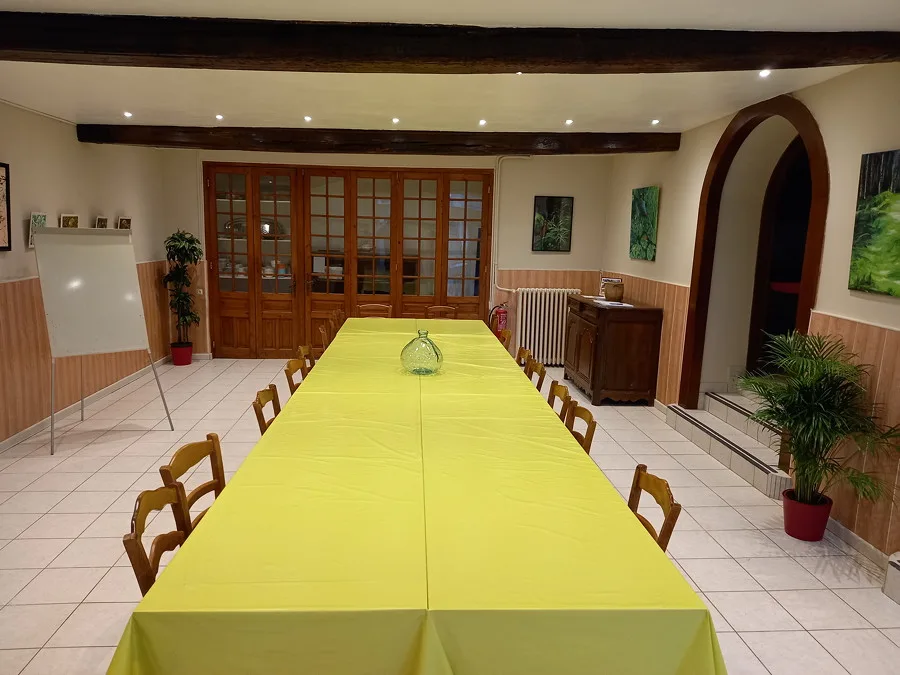 Grande salle de réception avec longue table dressée et nappe jaune