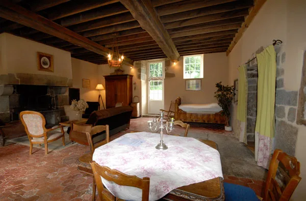 Grand séjour avec poutres apparentes, cheminée en pierre et grande table à manger