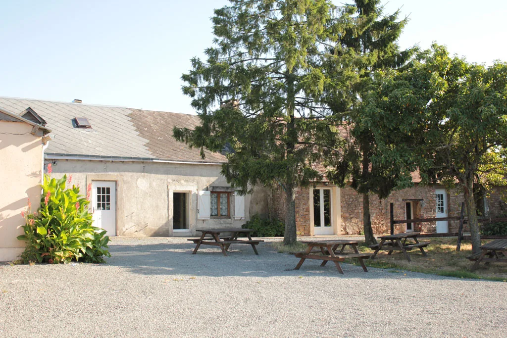 Cour intérieure avec tables de pique-nique en bois devant les bâtiments en pierre du domaine