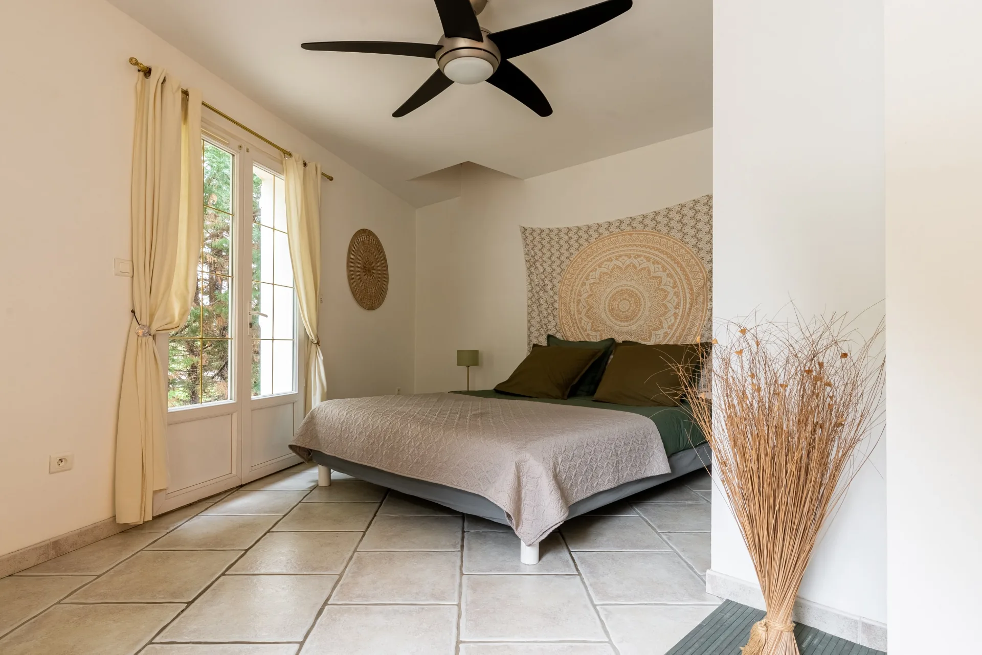 Chambre lumineuse avec grand lit double et porte-fenêtre donnant sur le jardin