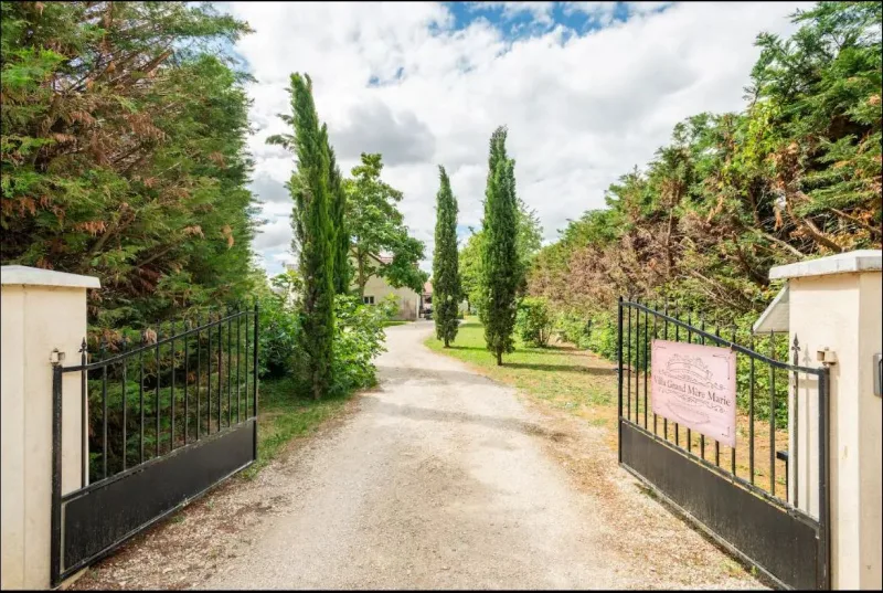 Portail d'entrée du domaine avec allée bordée de cyprès menant à la villa