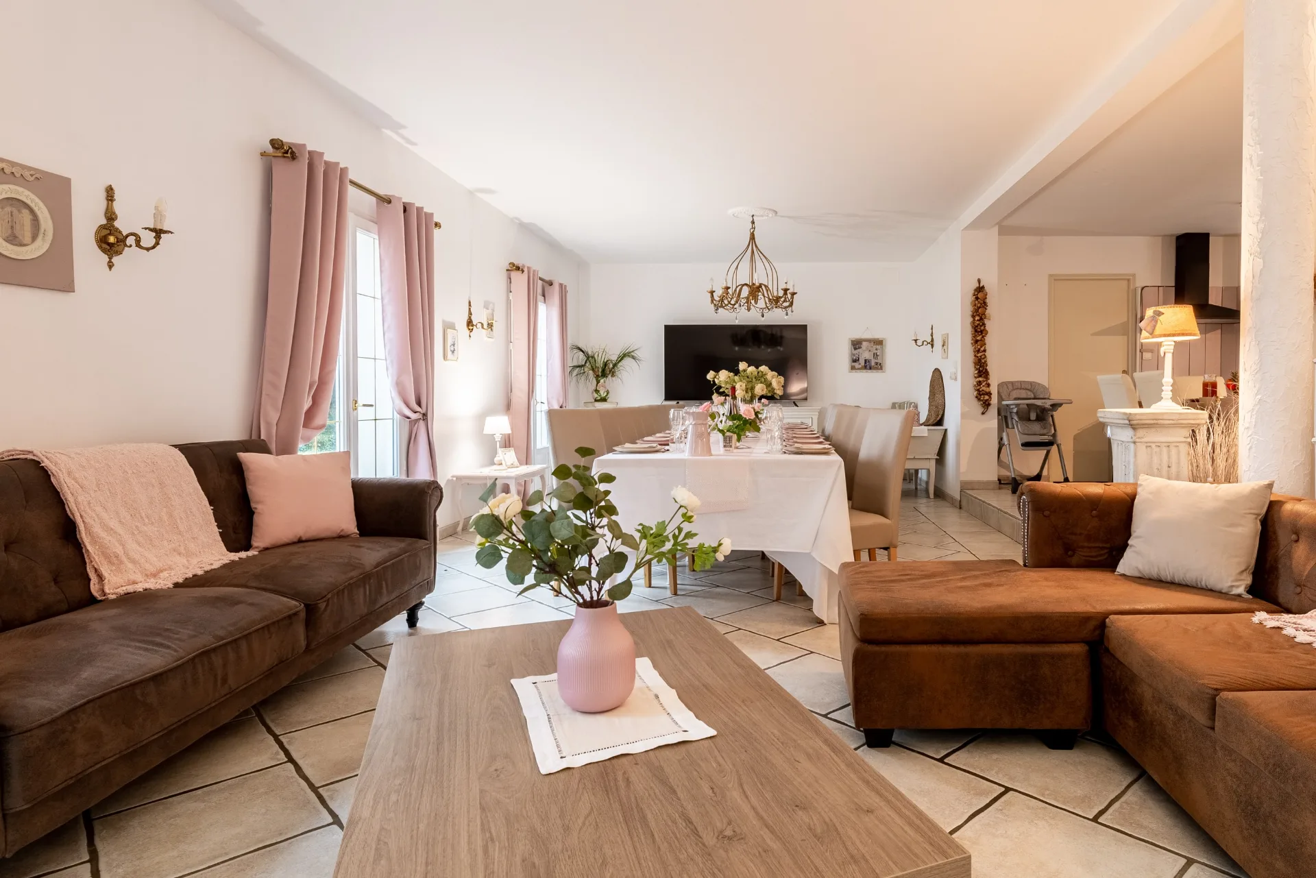 Grand séjour et salle à manger avec canapés et longue table dressée pour les convives