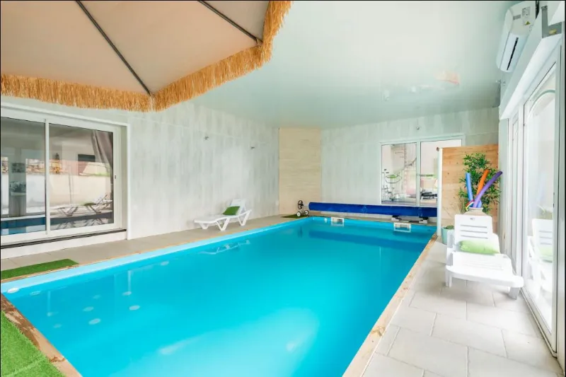 Piscine intérieure chauffée avec transats et grandes baies vitrées