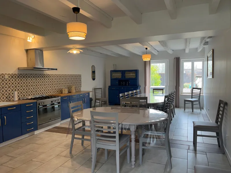 Cuisine intérieure moderne avec îlot central, four professionnel et grande table conviviale