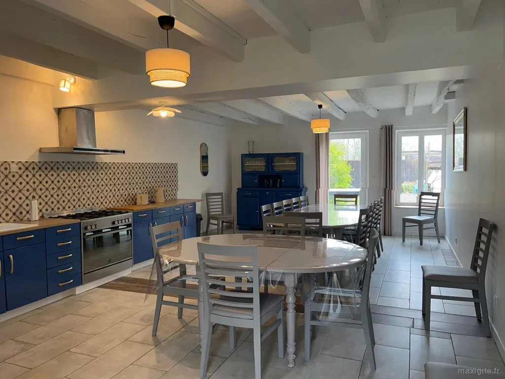 Cuisine intérieure moderne avec îlot central, four professionnel et grande table conviviale