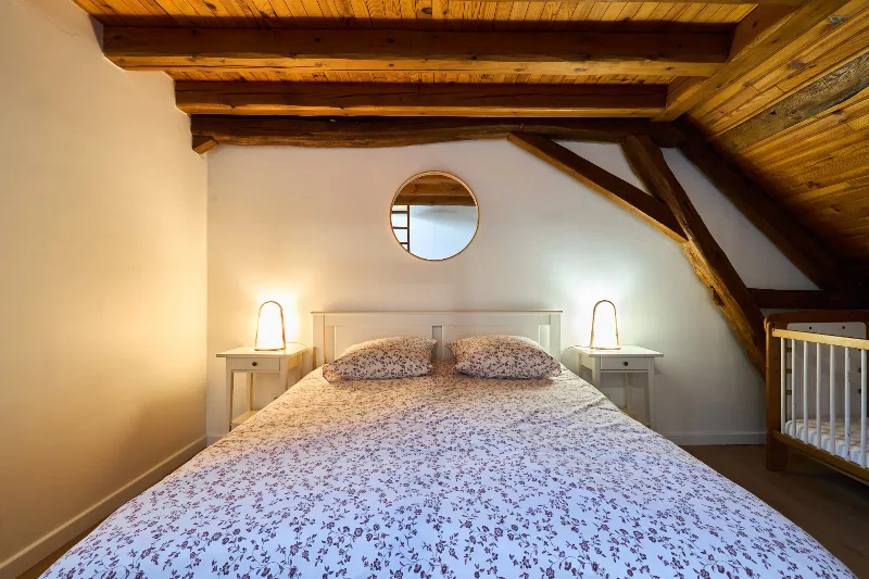 Chambre en mezzanine avec échelle en bois menant à un lit supplémentaire sous les combles