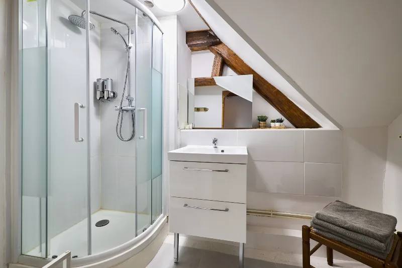 Chambre mansardée avec lit double, fenêtre de toit et poutres apparentes