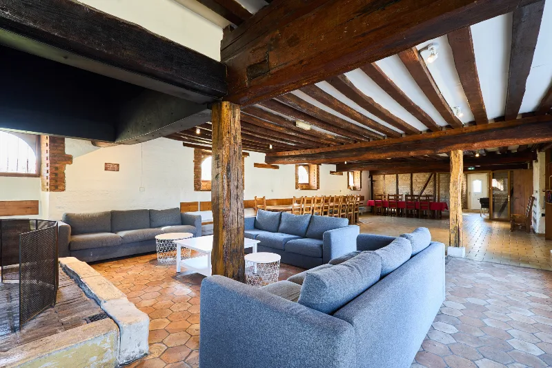 Immense pièce à vivre avec canapés et longue table en bois dressée pour un grand groupe