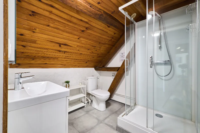 Salle de douche à l'italienne avec double vasque et rangements sous les poutres