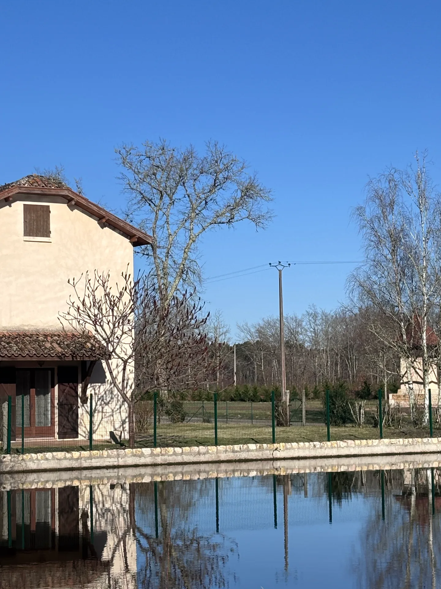 Façade de la Maison du Lac avec grande baie vitrée ouverte sur le jardin
