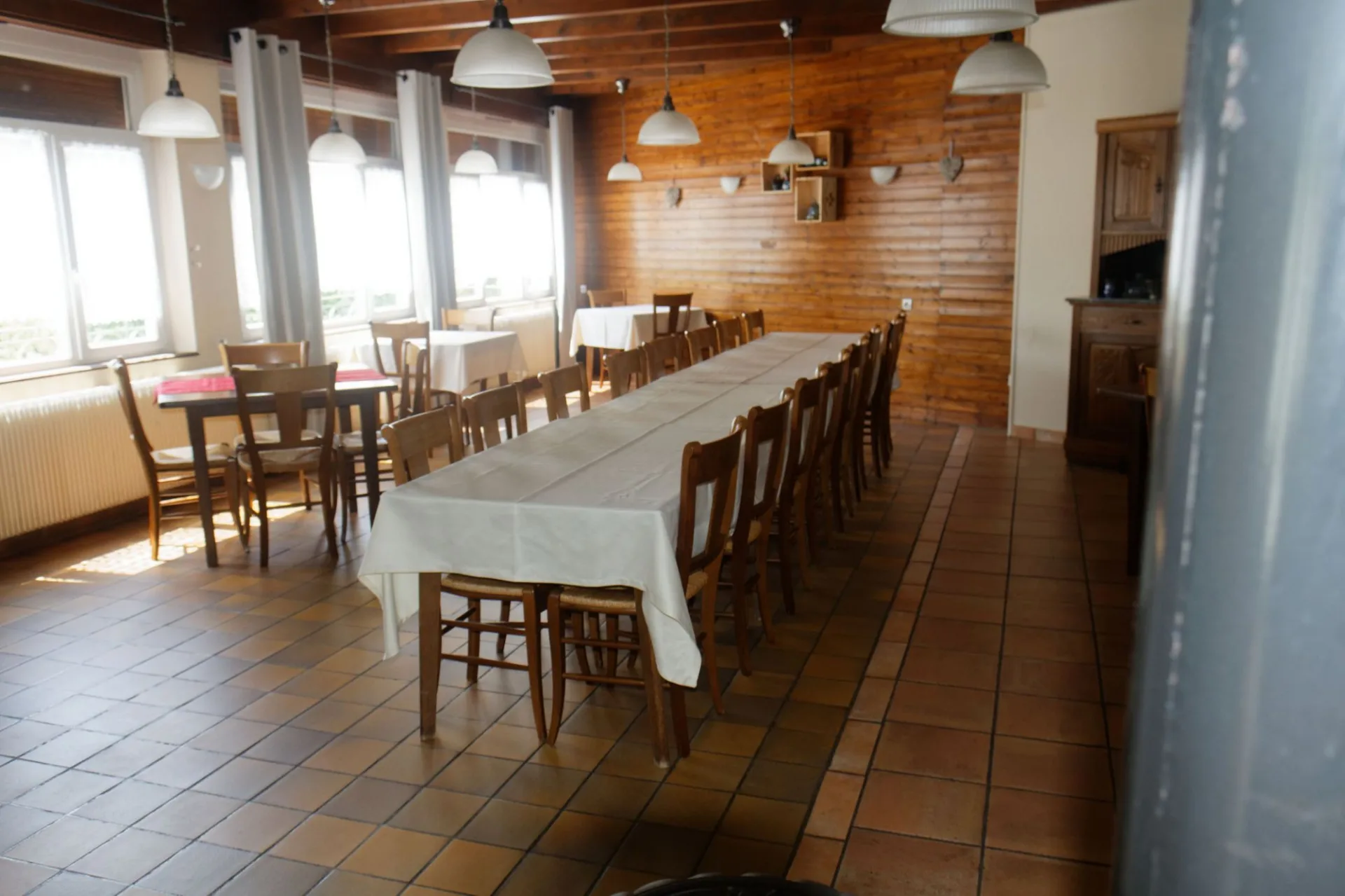 Grande salle à manger avec longue tablée en bois pour recevoir tout le groupe