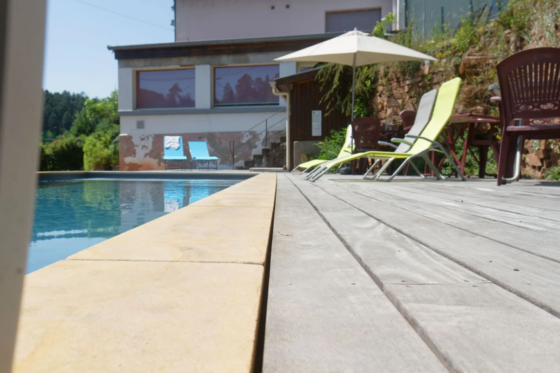 Piscine vue de la terrasse en bois avec jardin et route à l'arrière-plan