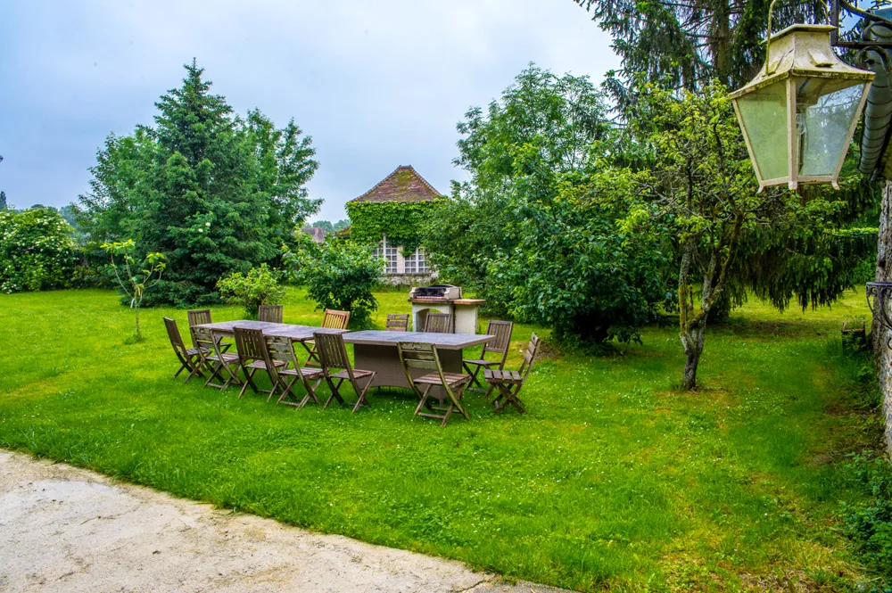 Grande table en bois dressée dans le jardin ombragé pour un repas en groupe