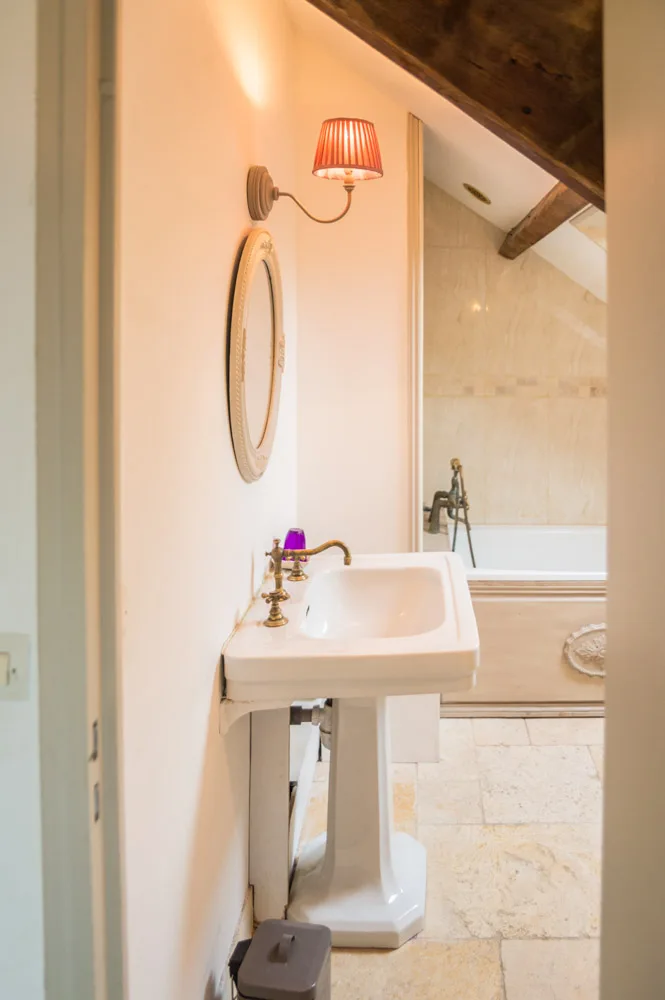 Salle de bain avec baignoire, vasque et carrelage en pierre claire