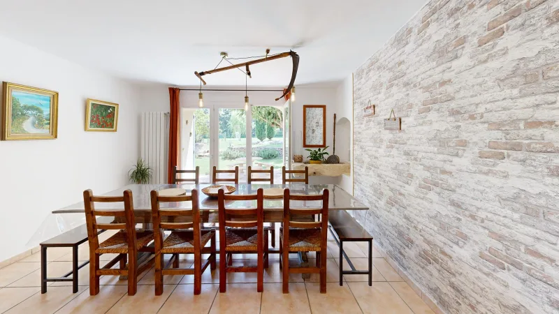 Grande salle à manger avec table en bois pour dix convives et mur en pierres apparentes