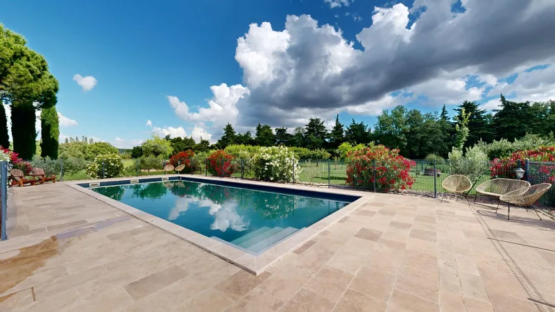 Piscine rectangulaire entourée d'une terrasse en pierre et d'un jardin fleuri de lauriers roses