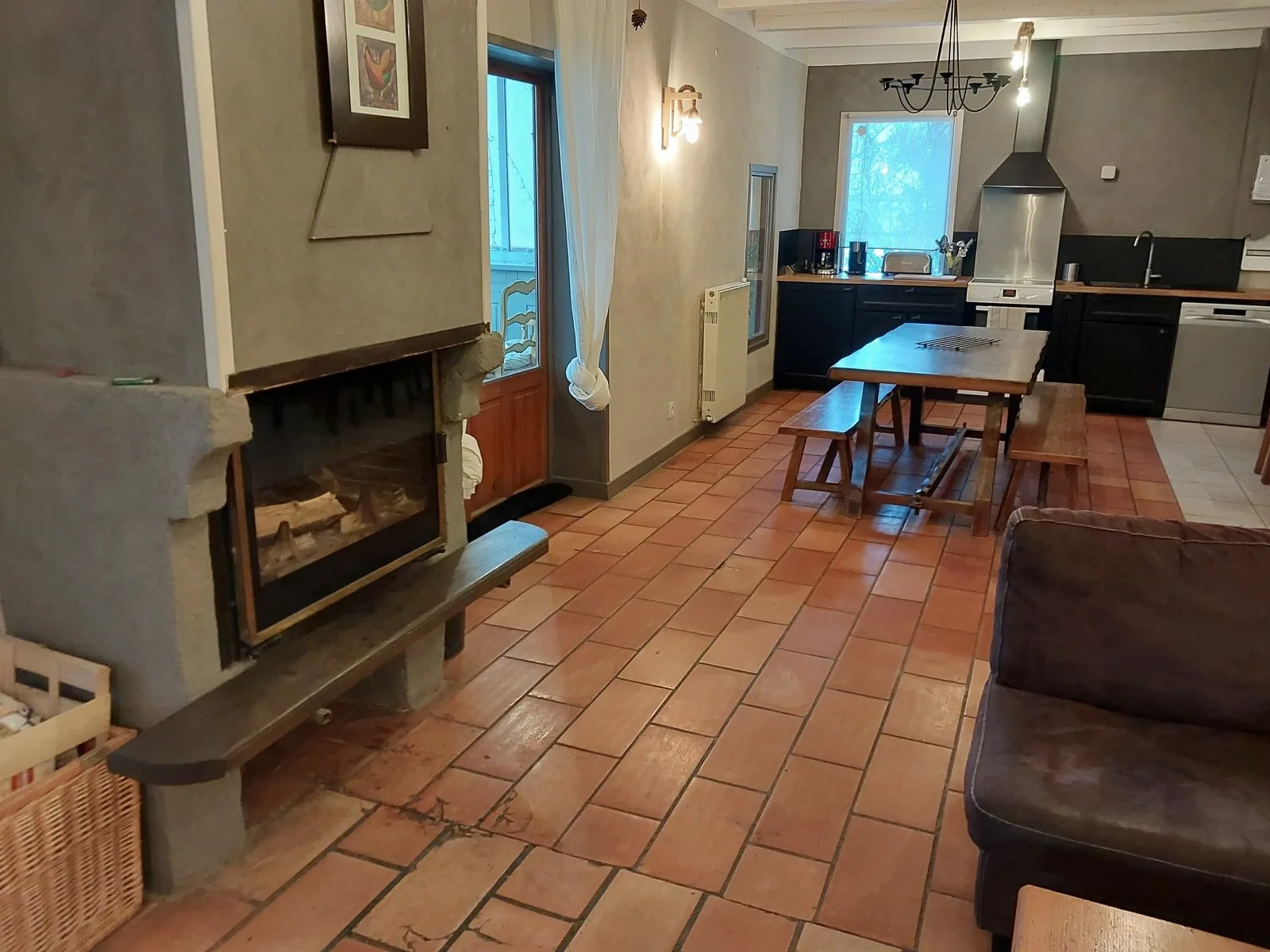 Cuisine ouverte équipée avec plan de travail, hotte et grande table en bois pour les repas