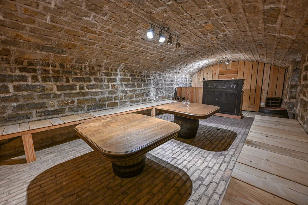 Cave de convivialité voûtée avec tables sur tonneaux pour dégustations