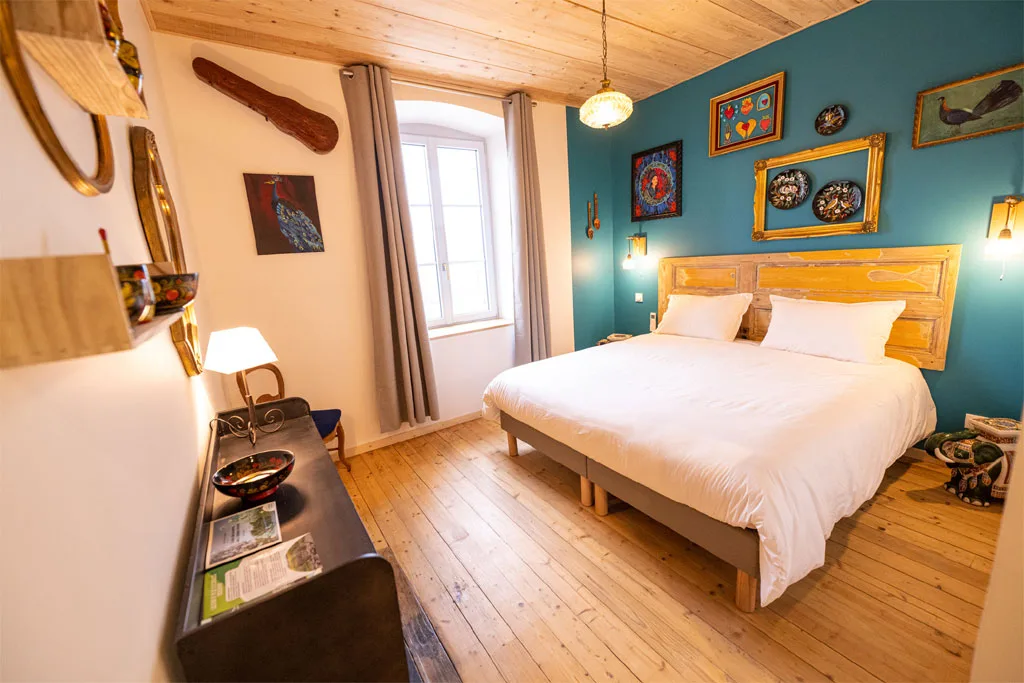 Chambre double avec mur bleu canard et suspension en rotin