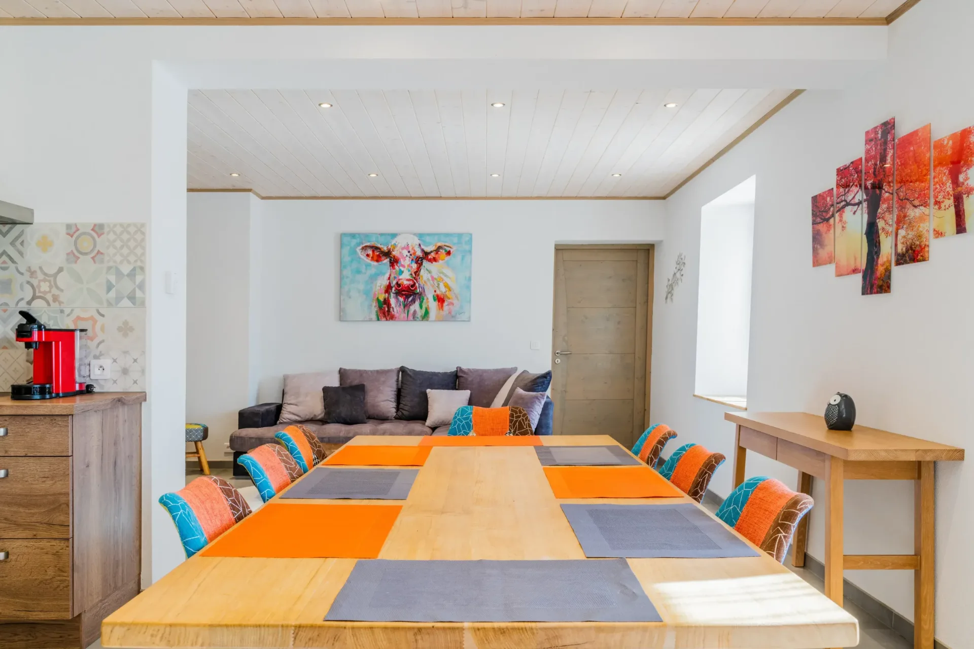 Salle à manger conviviale avec grande table en bois pour groupe et tableau d'une vache