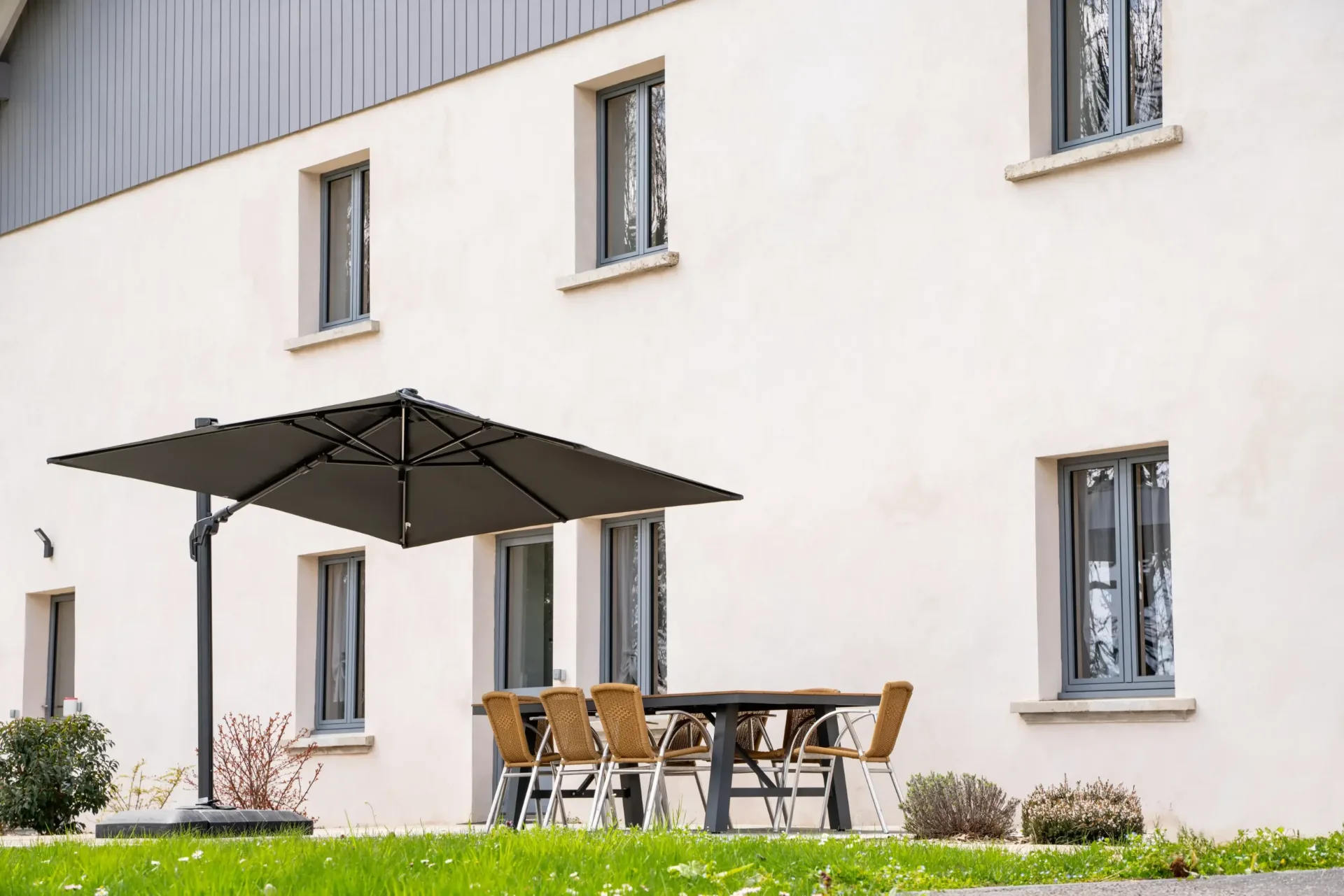Terrasse extérieure ombragée avec grands parasols, table et chaises en rotin