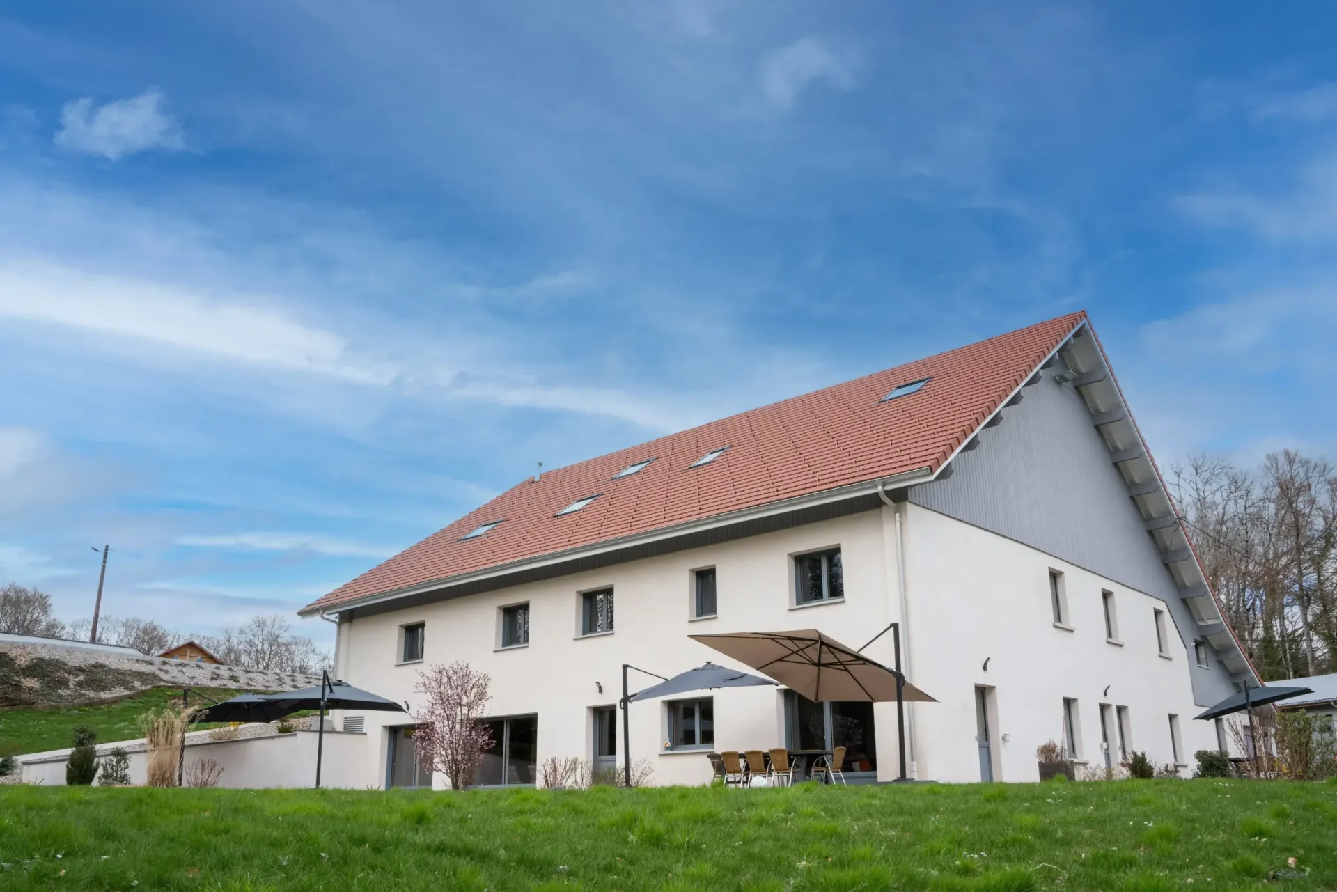 Vue arrière du bâtiment avec terrasses et grande pelouse verdoyante